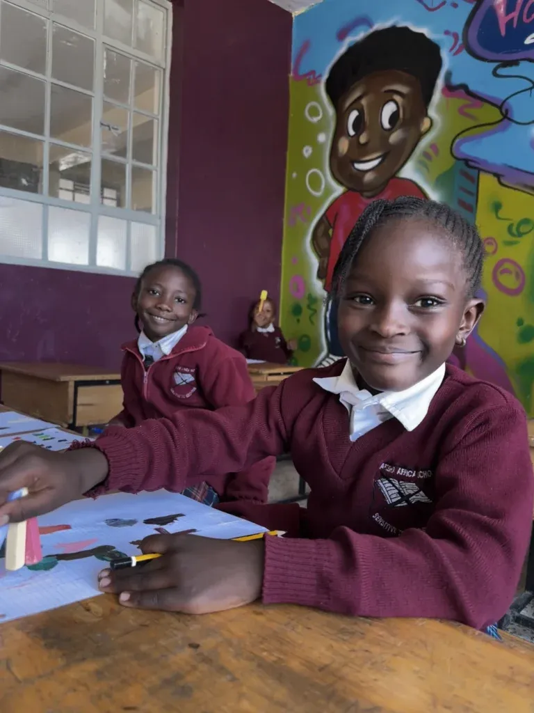 Zwei fröhliche Kinder im Schulzimmer lachen begeistert – Freude am Lernen in einer unterstützenden Umgebung.